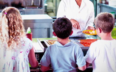 Cheerful,Woman,Serving,Food,To,Schoolchildren,In,Canteen